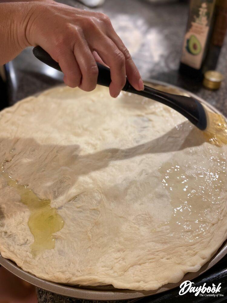 pizza dough being brushed with avocado oil