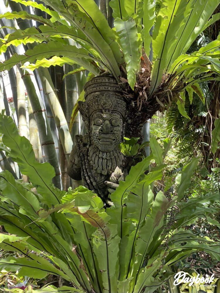 A wood carving amongst palm trees and bamboo in a Florida botanical garden.