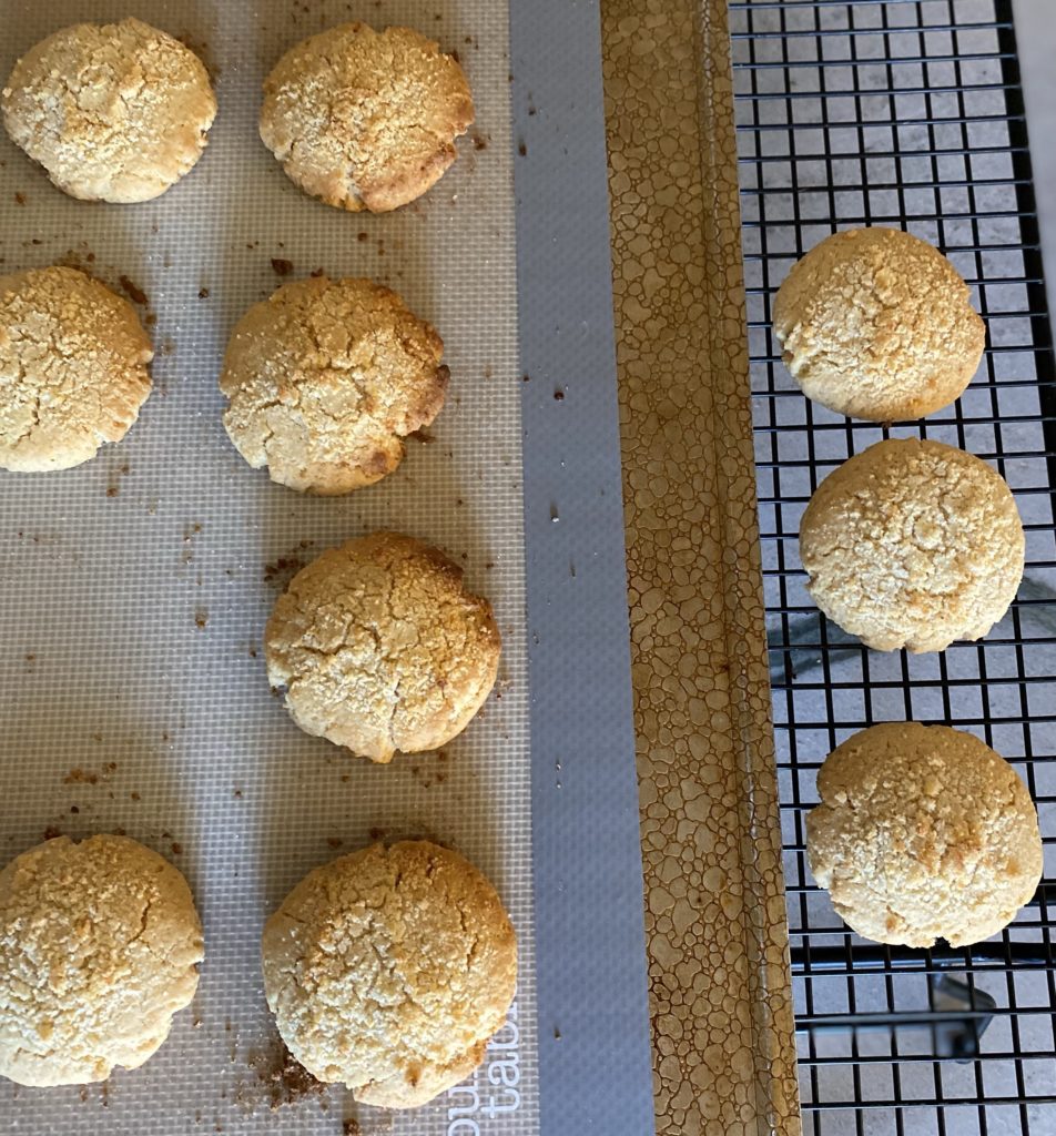 A cookie tray of baked apple crumble cookies beside a cooling rack.
