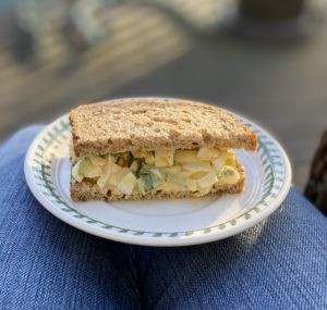 Half of an egg salad sandwich on a small white plate.
