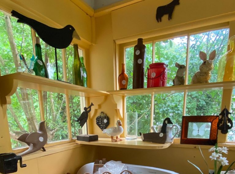 Collectibles in a bright sunny yellow window at an estate sale