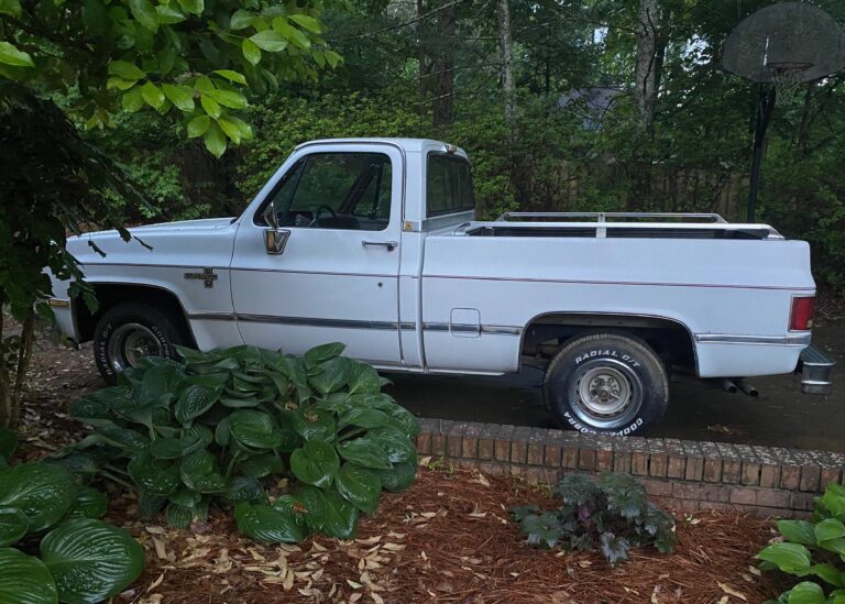 Side view of a 70s Chevy Silverado truck parked by a brick wall